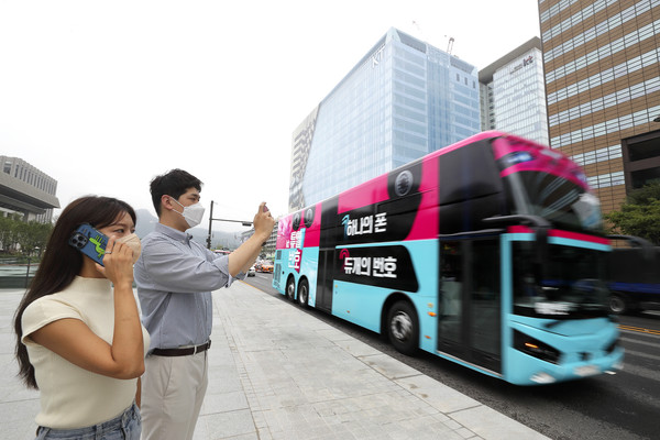 KT 고객이 ‘듀얼번호 버스’를 촬영해 SNS 올리는 인증샷 이벤트에 참여하는 모습. ⓒKT